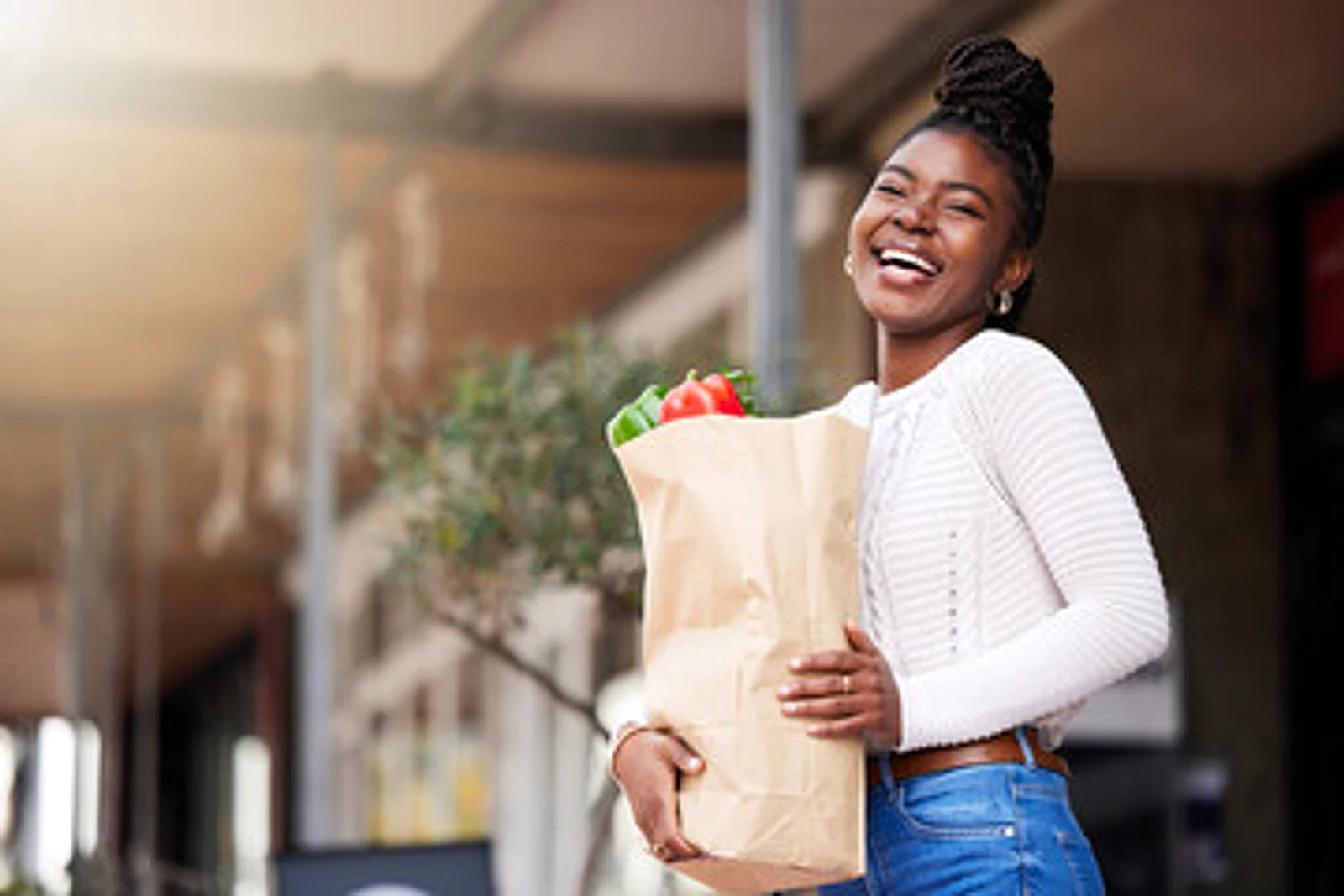 Happy shopper holding a paper bag of fresh peppers